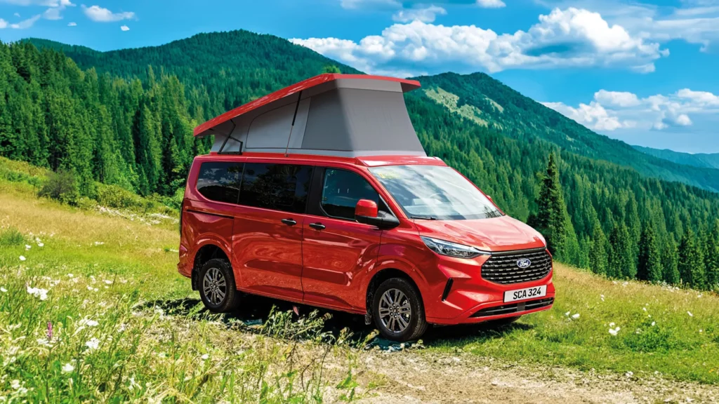 Ford Campervan mit Aufstelldach SCA 324 in Rot, geöffnetem Dach und Panoramablick in den Bergen – ideal für Vanlife und Campingausbau.