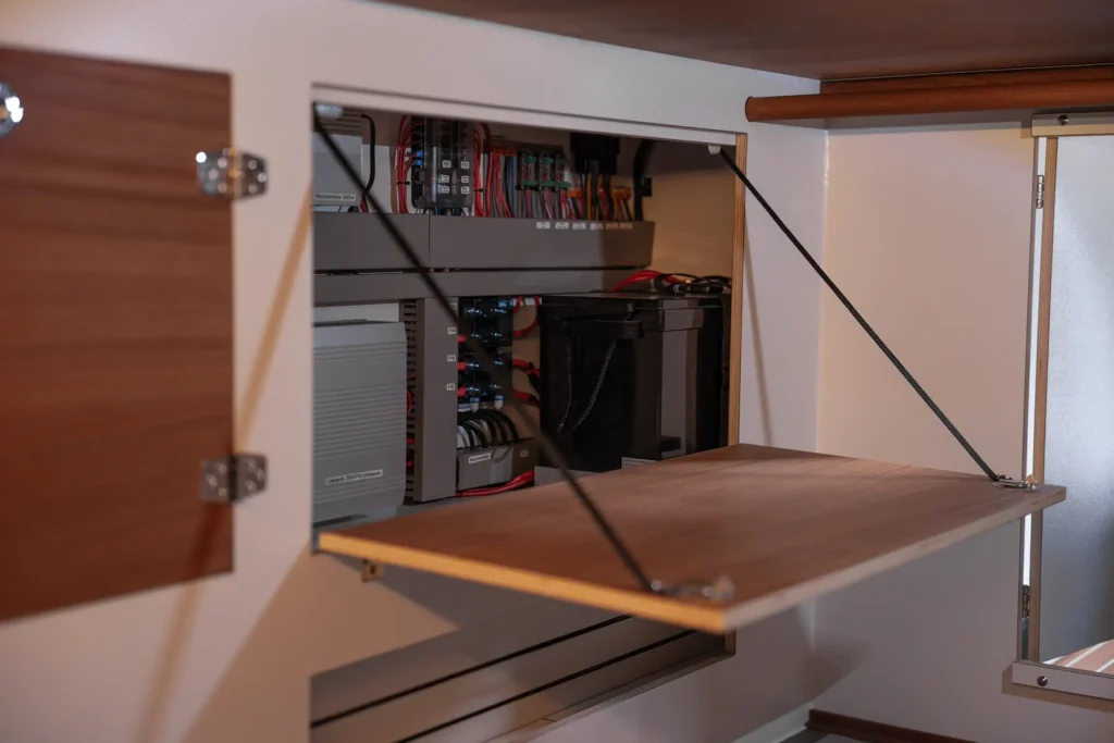 Präzise verbaute elektronische Ladekomponenten und Solarregler im Technikbereich eines ausgebauten Campers.
